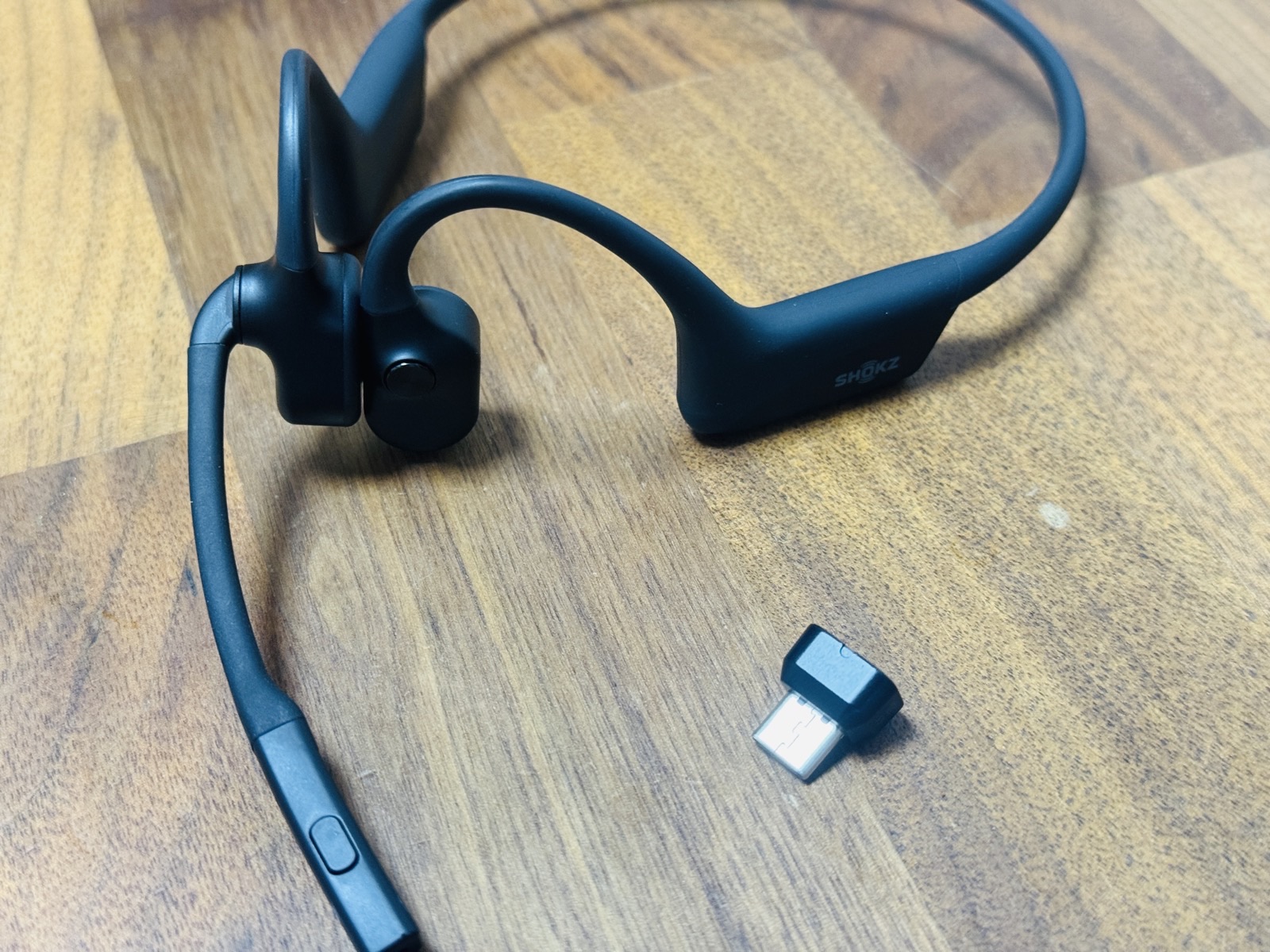 骨伝導ヘッドセット Shokz OpenComm2 本体と、付属の USB ドングル